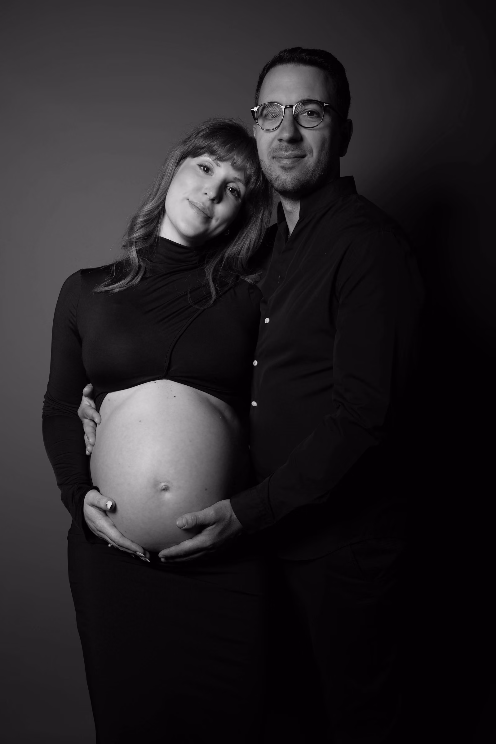 Portrait en noir et blanc d'un couple en attente, la future maman tenant son ventre rond
