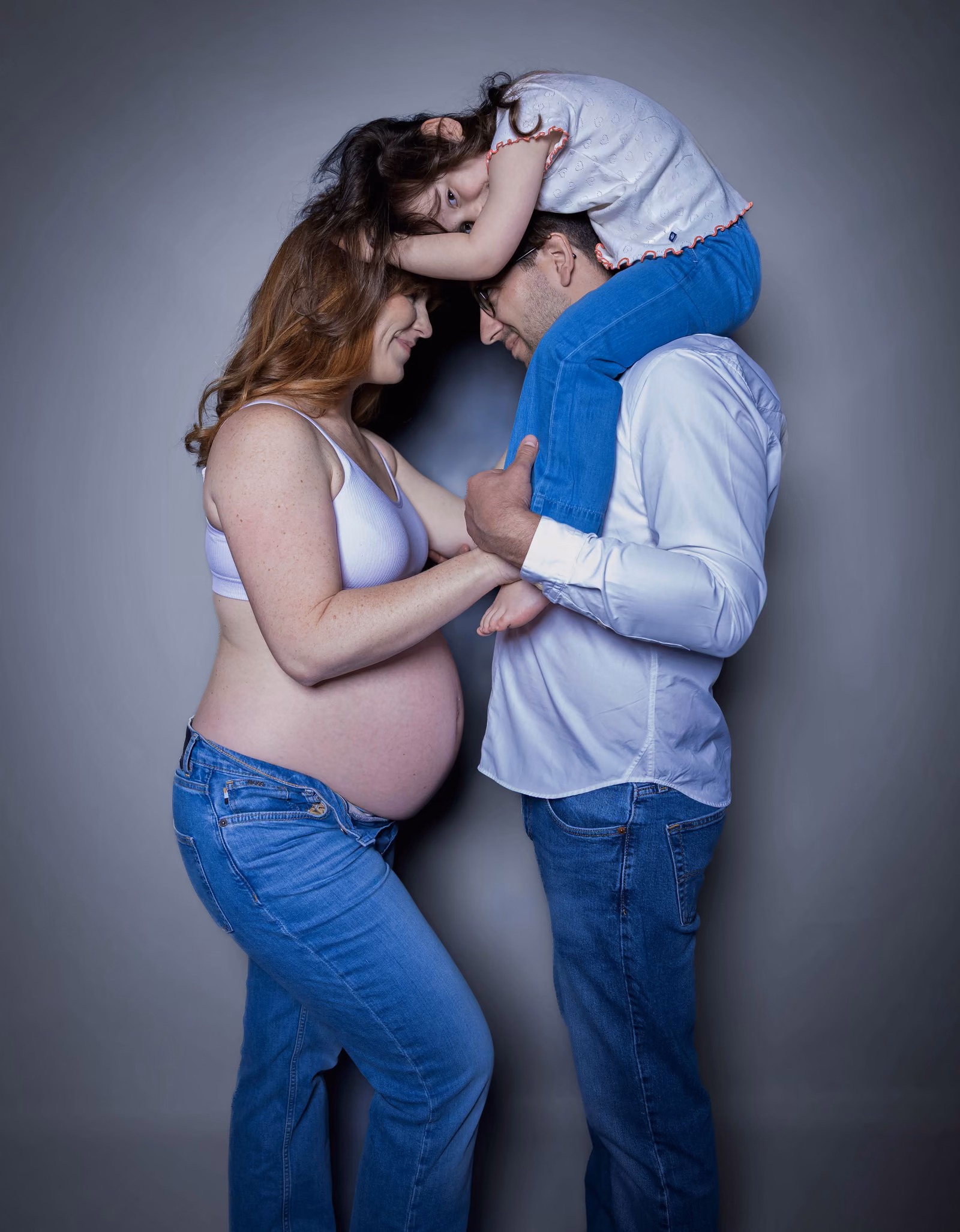 Les futurs parents front contre front, leurs mains réunies sur le ventre arrondi