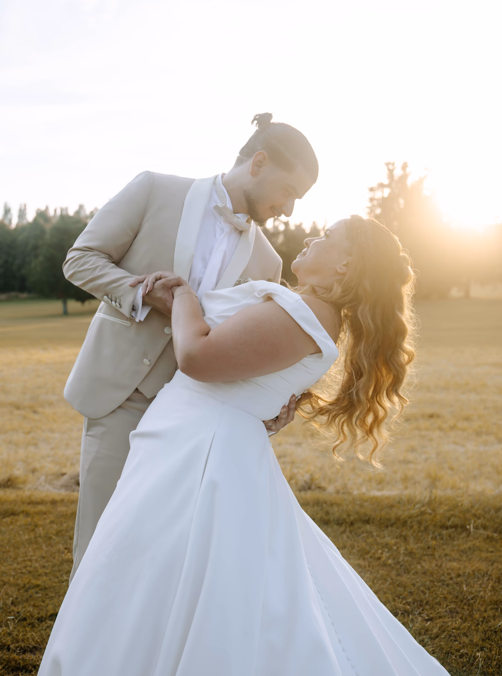 Le marié penche la mariée en arrière pour l'embrasser, dans la lumière dorée