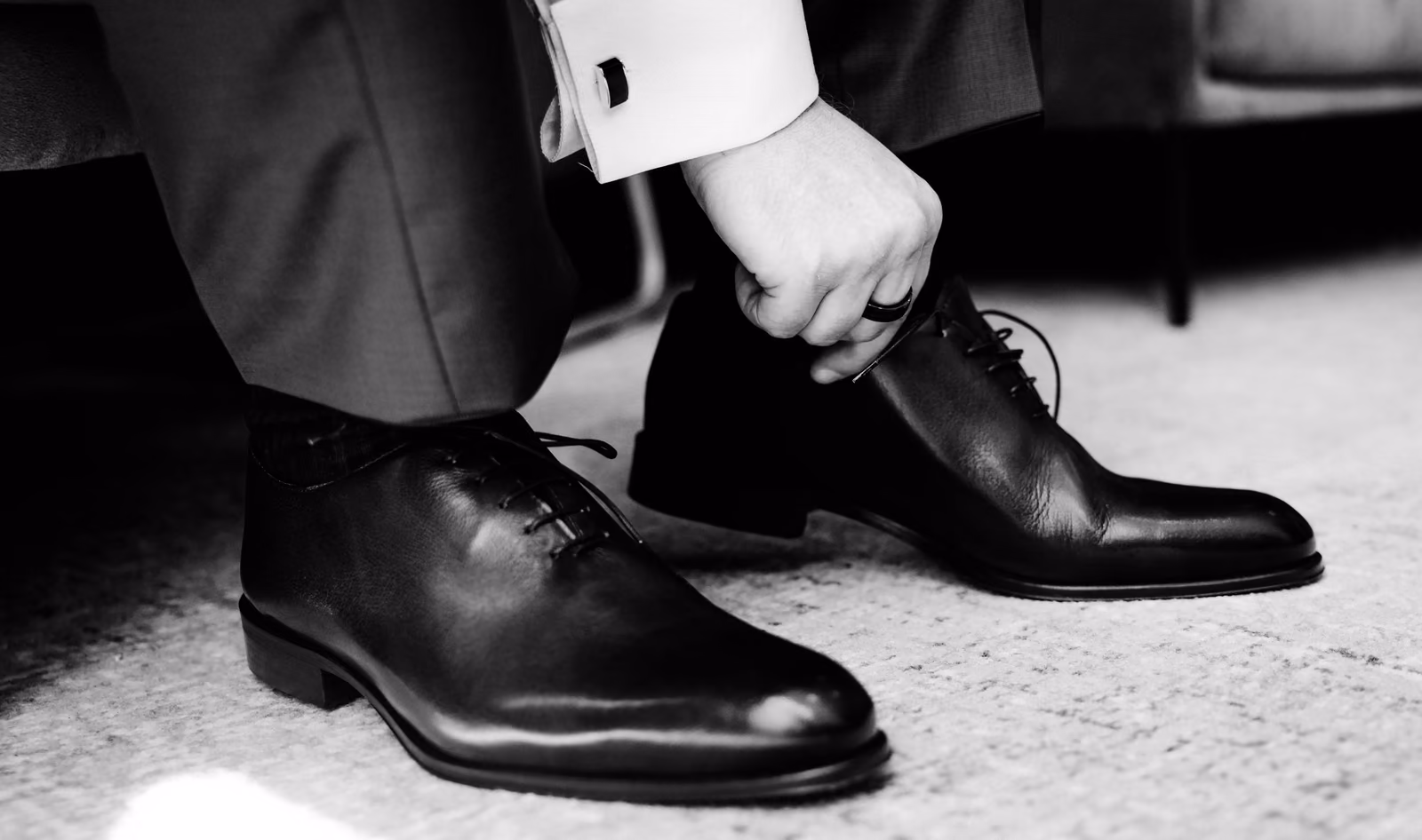 Le marié lace ses chaussures de cérémonie, détail en noir et blanc