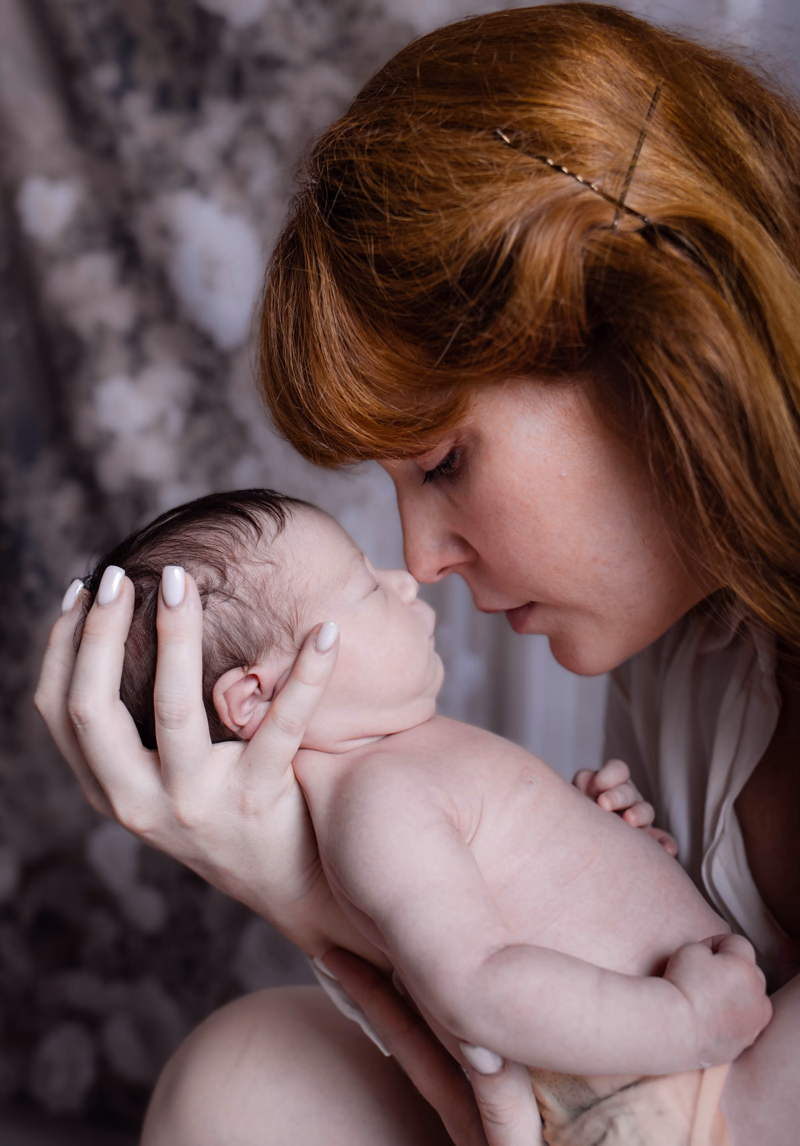 La maman tient son nouveau-né tout contre son visage, les yeux fermés